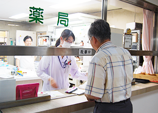 薬局カウンターで来訪者に対応する薬剤師の様子